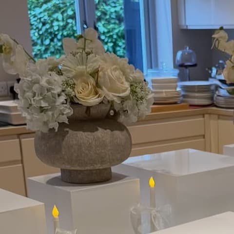 A close detail of ivory florals, plinths, and candles within a tablescape.